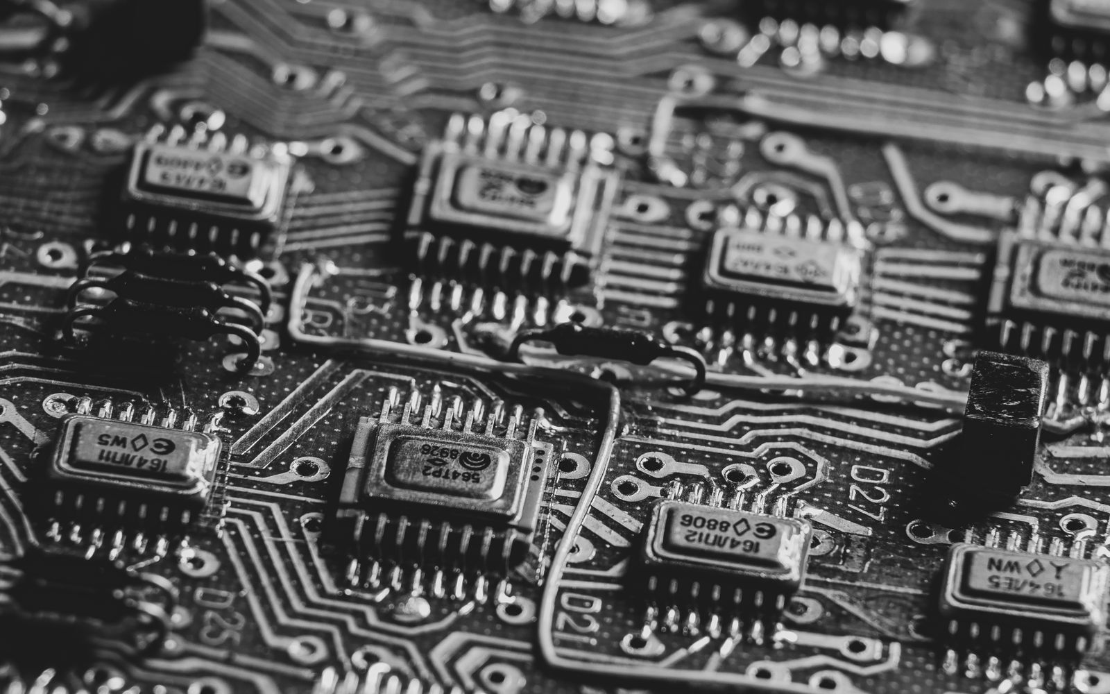 A black and white macro of microchips laid out across a circuit board