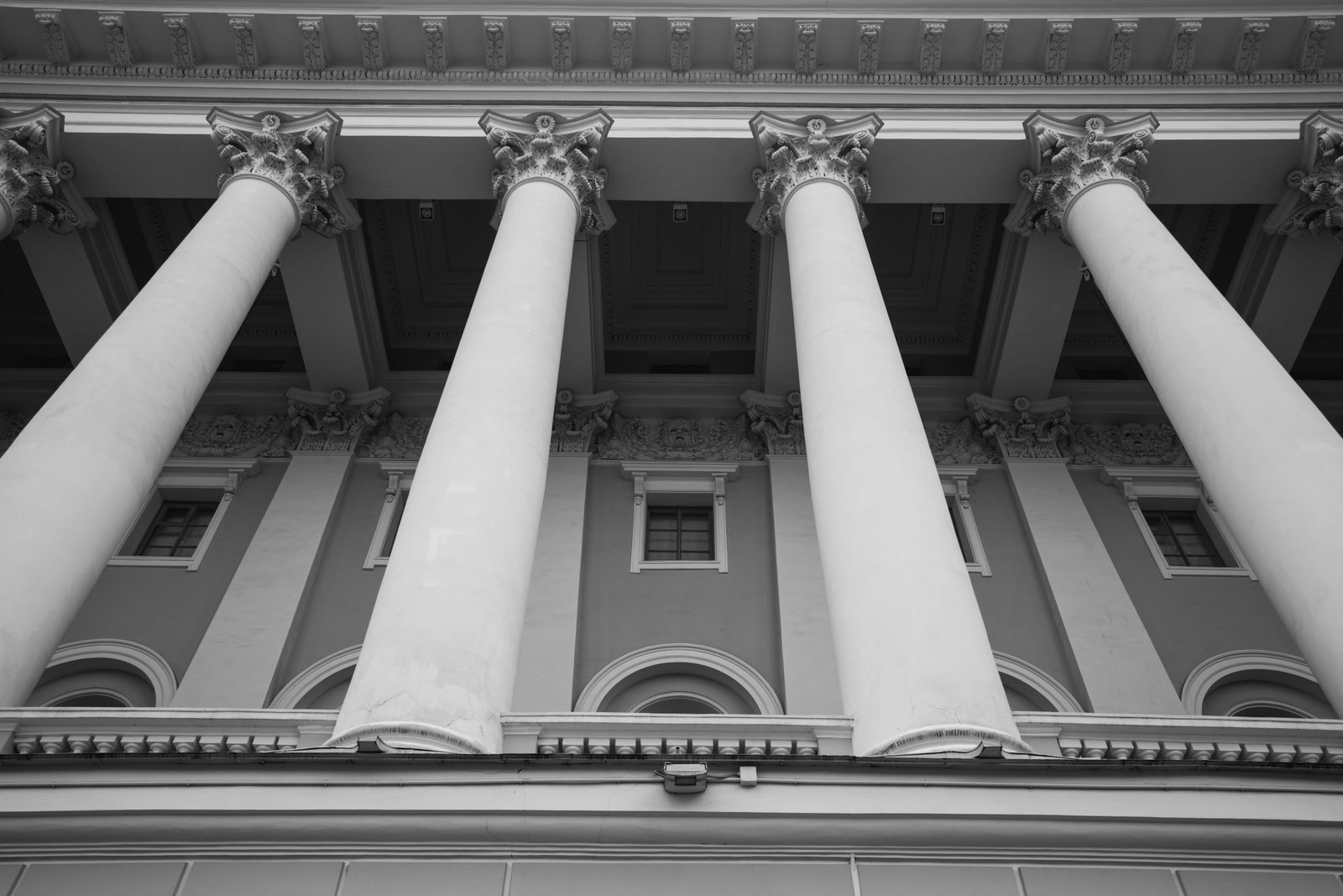Classical columns of a public building, photographed from below in black and white