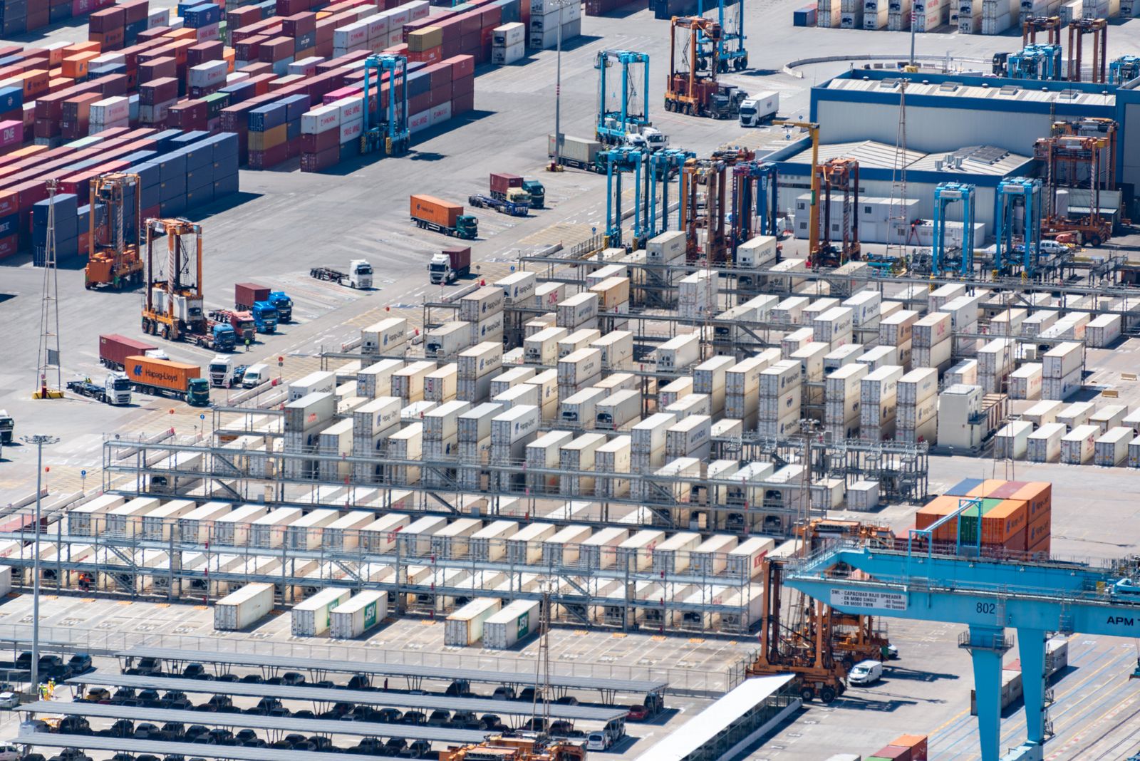 A container terminal from above, rows of stacked containers and cranes