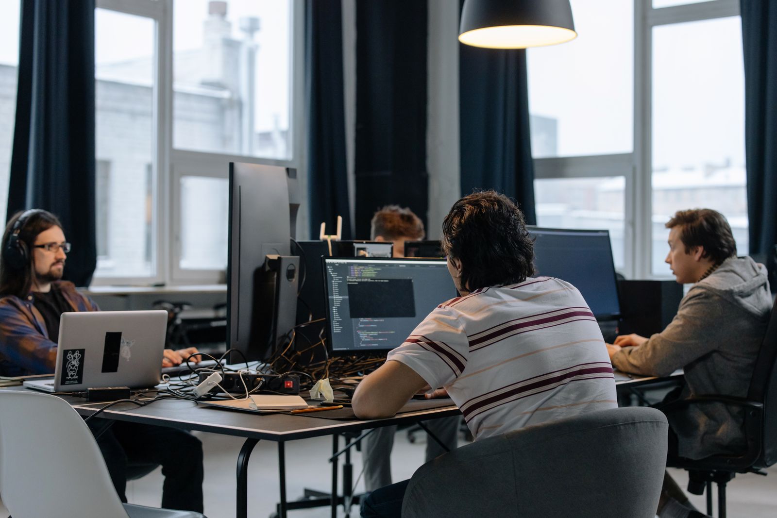 A small engineering team at work across code-filled monitors in a bright office