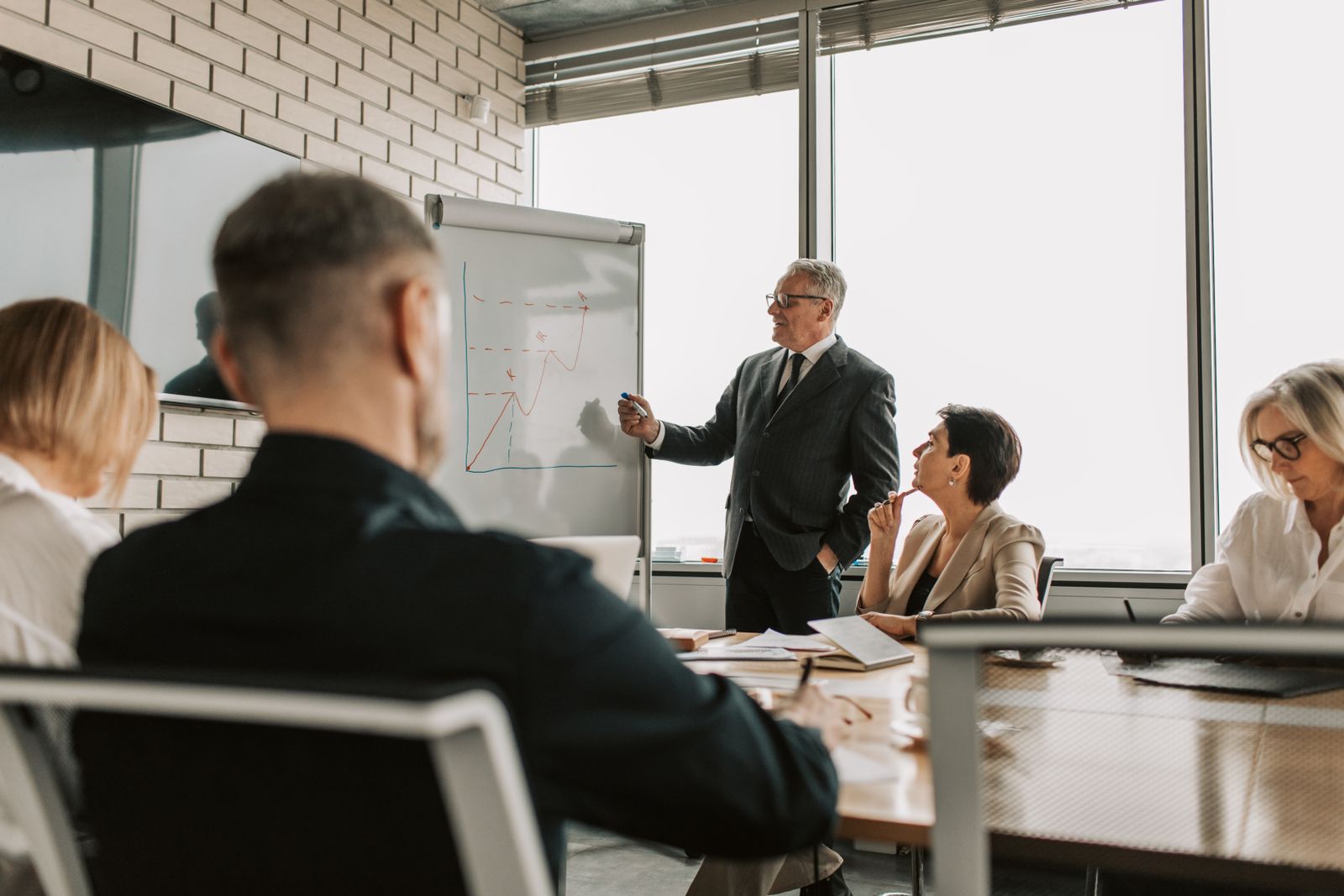 A senior engineer walking a small table through a chart on a flipchart