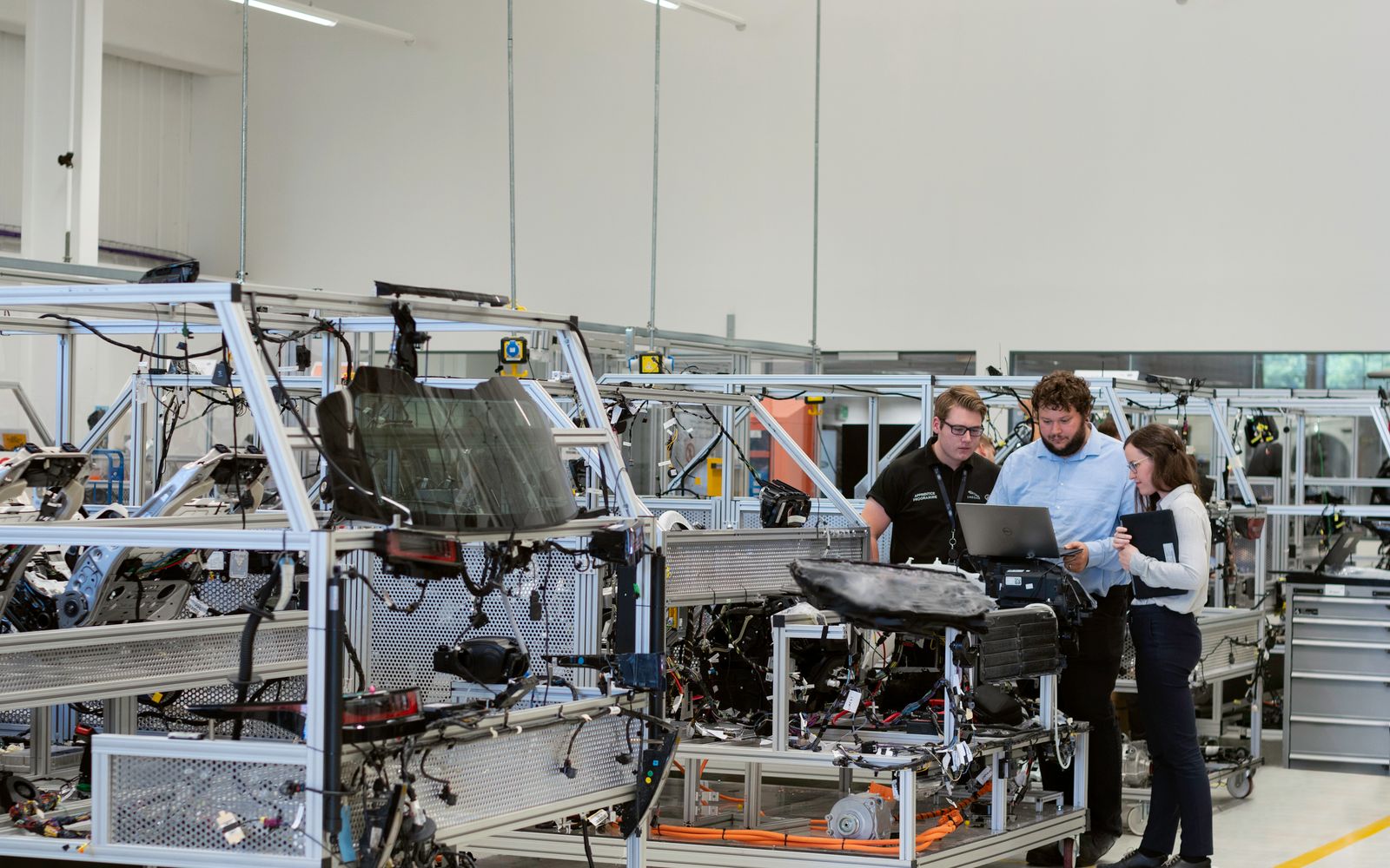 Three people over a laptop on a bright production floor