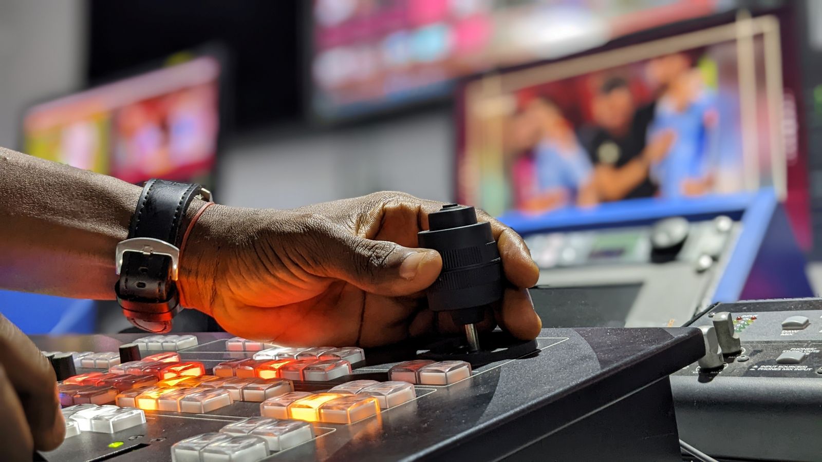 A hand on a vision mixer cutting between live football feeds