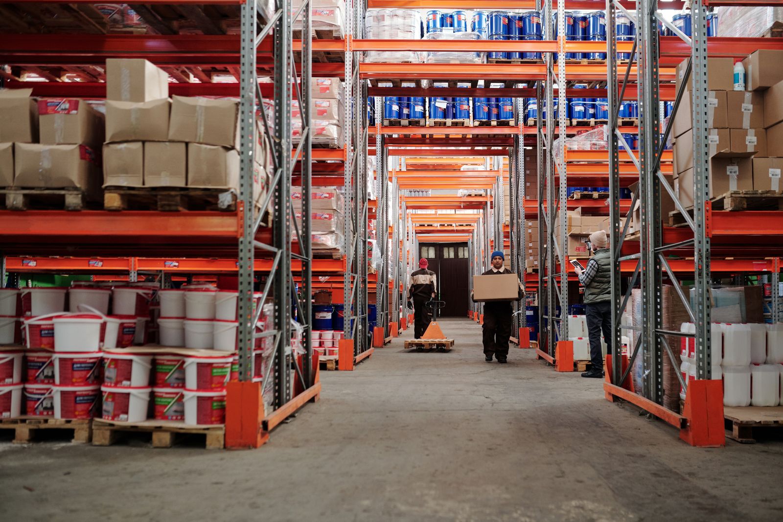 A warehouse aisle of racked stock with workers moving goods